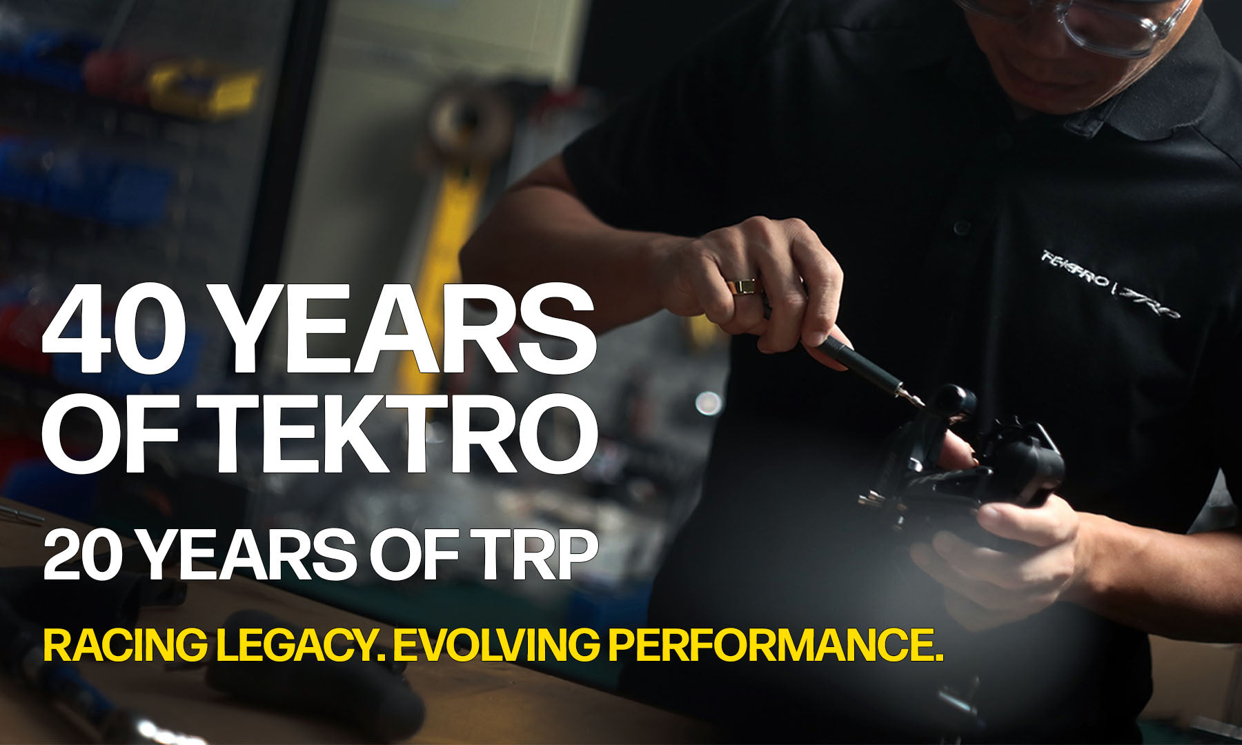 A man in a black Tekto racing shirt works on a race car in a garage, with large text overlay reading '40 YEARS OF TEKTO', '20 YEARS OF TRP', and 'RACING LEGACY. EVOLVING PERFORMANCE.