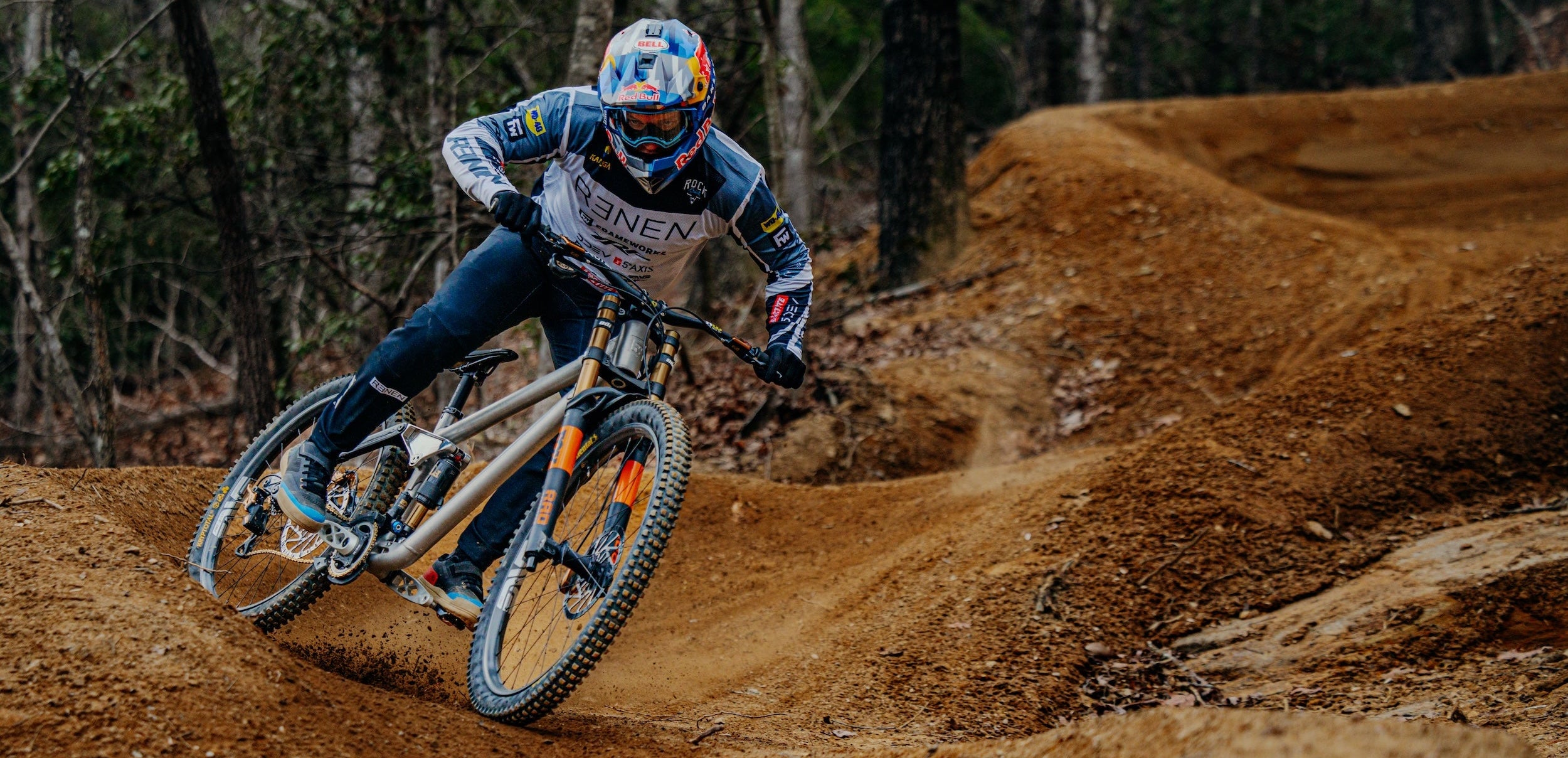 Biker in action on a dirt track with trees in the background