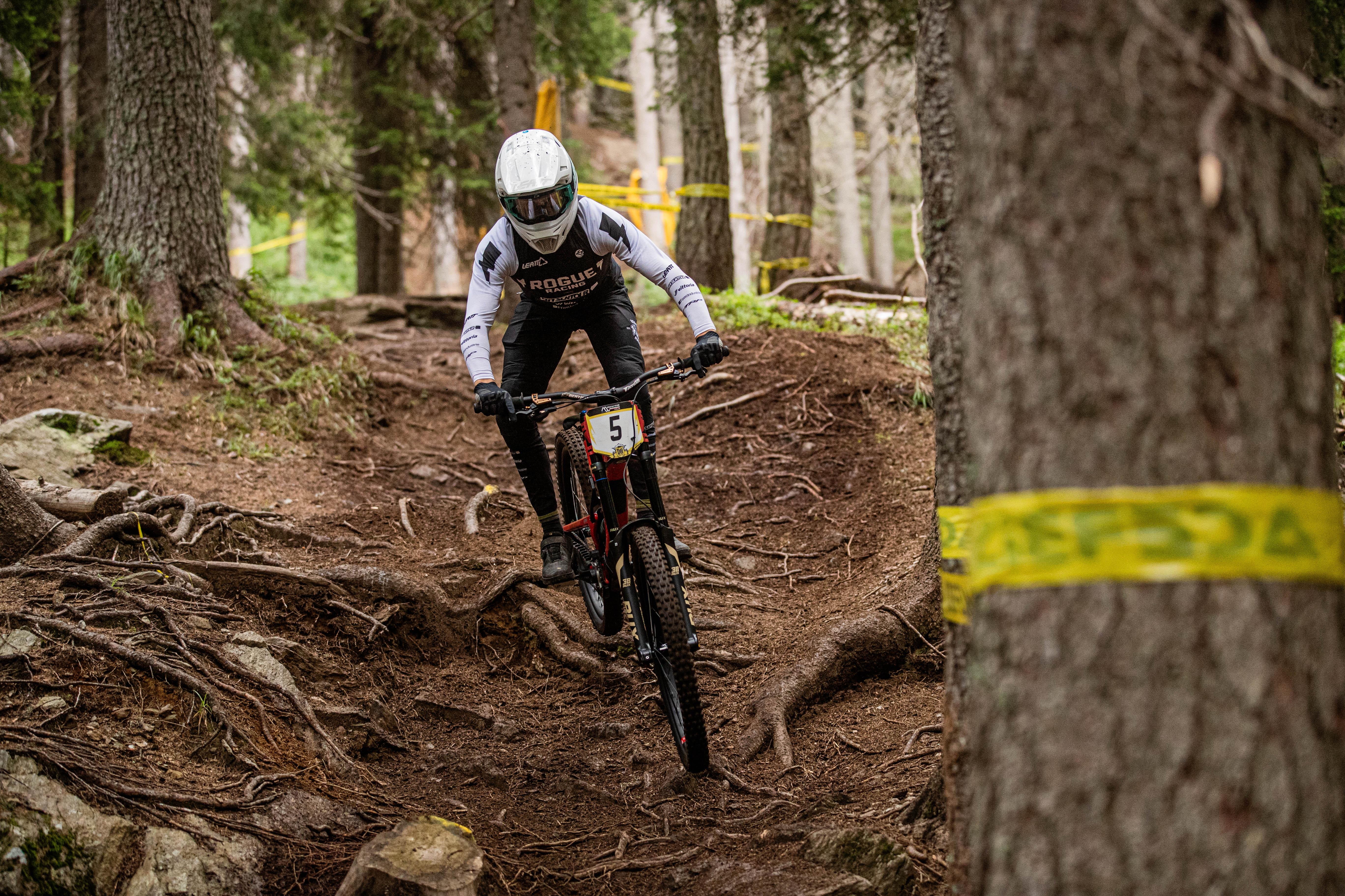 Mountainbiker navigating a dirt trail with trees and caution tape in the background