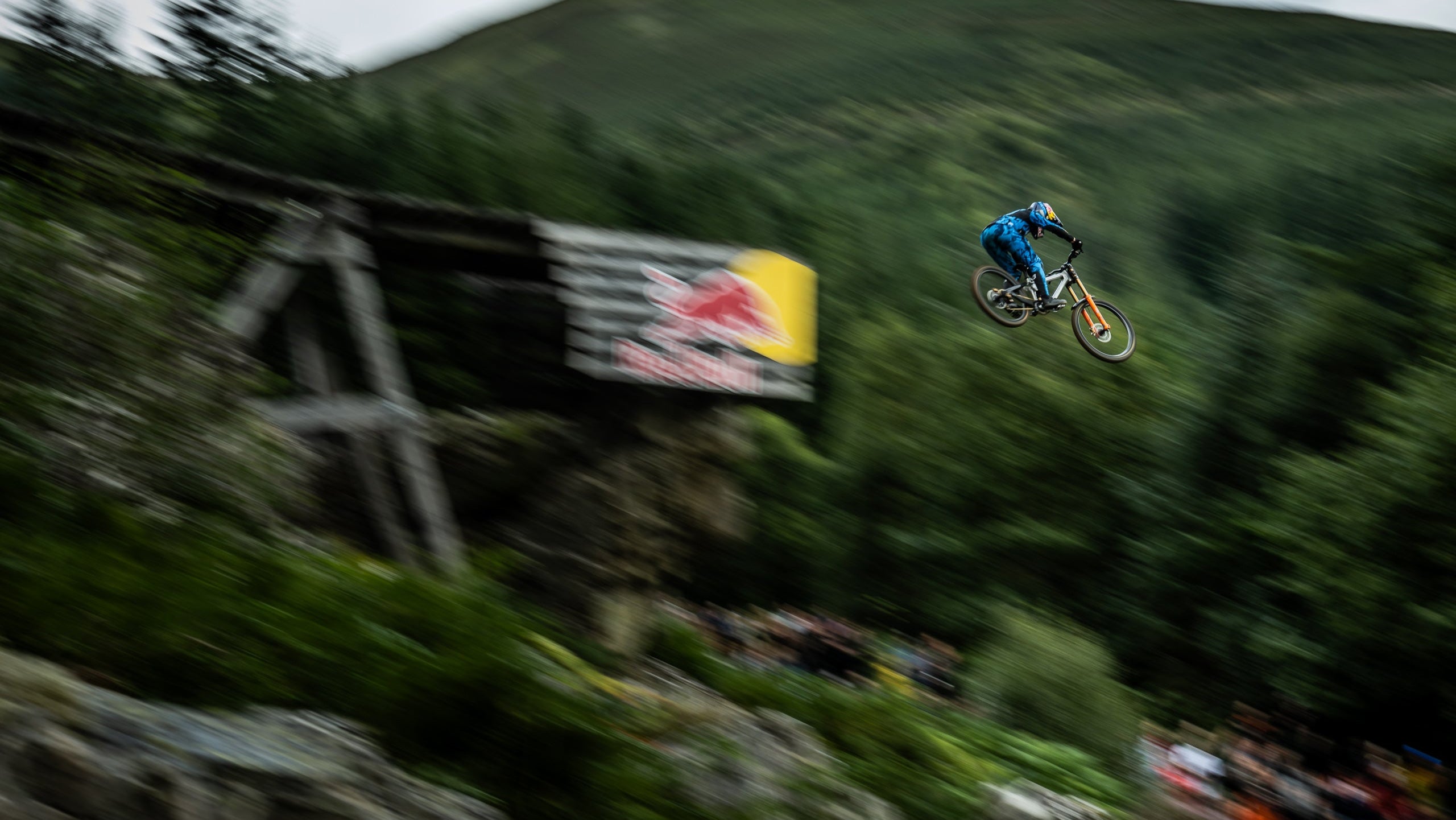 Biker in mid-air performing a stunt with a Red Bull banner in the background