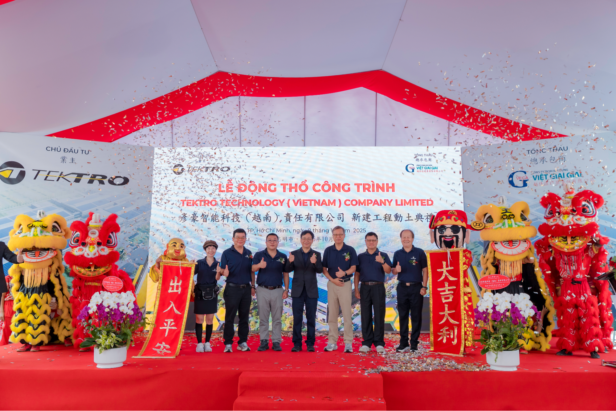 A group of men standing on a red carpet under a white tent, with lion dancers on both sides, confetti falling, and a large Vietnamese ceremony backdrop reading Tektro Hydrology (Vietnam) Company Limited.