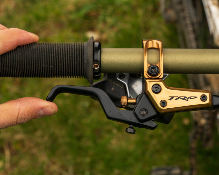 Close up of TRP EVO brake lever on a  mountain bike handlebar with a hand pulling the lever